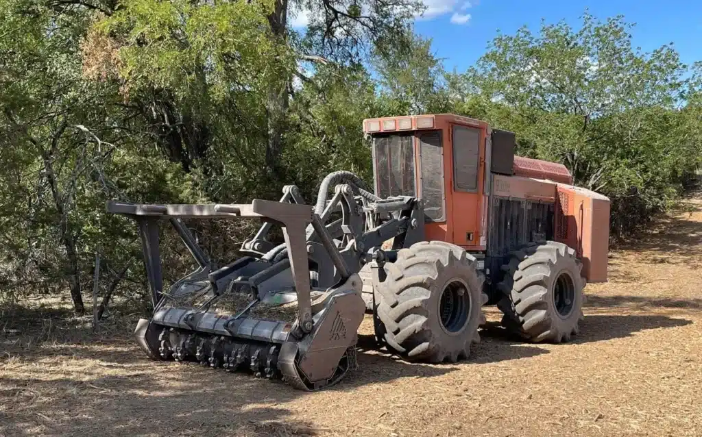 Forestry mulching machine positioned beside dense Texas brush